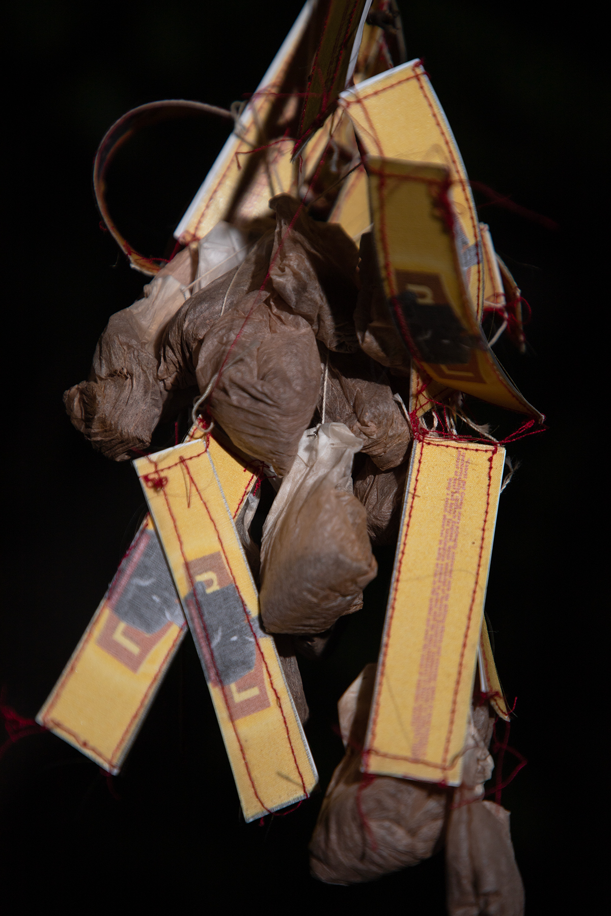A close-up of used Lipton tea bags are suspended in mid-air. The tea bags have yellow labels with red stitching on the front and back. There is an image of Sir Thomas Lipton on the front. 